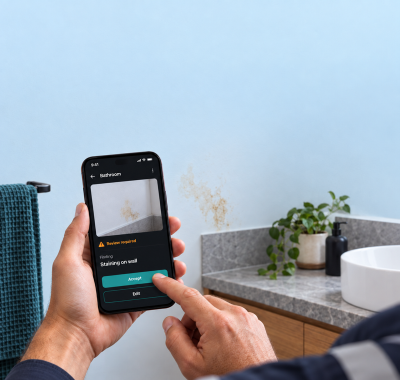 Australian suburban rental property with an inspector at the front door, phone raised, mid photograph